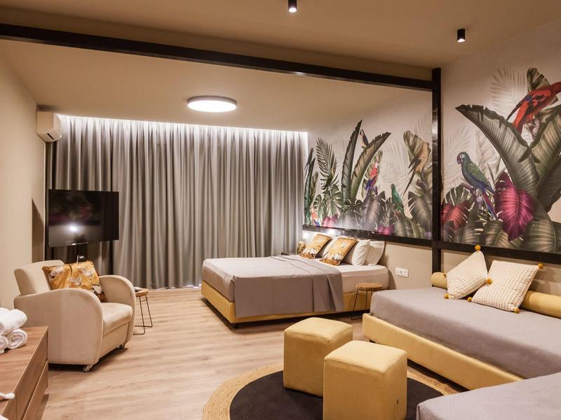 Camera d'hotel moderna con letti, area salotto e decorazioni murali.