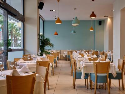 Nowoczesna restauracja hotelowa z starannie nakrytymi stołami i dużymi oknami.