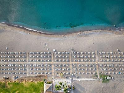 Aerial view of an organized sandy beach with sun umbrellas and a view of the blue sea.