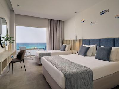 Modernes Hotelzimmer mit Doppelbett und Meerblick durch große Fenster