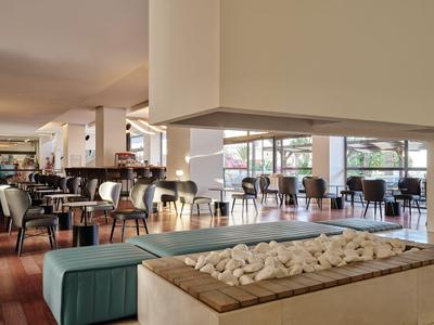 Nowoczesna strefa lounge w hotelu z miejscami do siedzenia i centralnym kamiennym kominkiem.