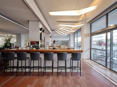 Nowoczesny bar z wysokim kontuarem i stołkami obok dużych okien i drzwi tarasowych.