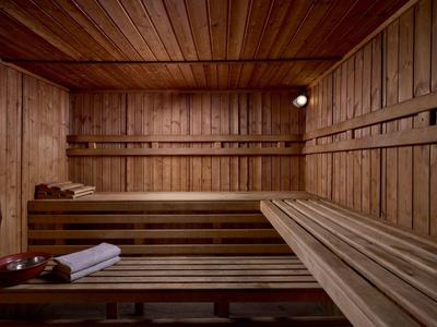 Sauna room with wooden walls, benches, a towel, and sauna bowls.
