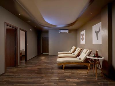 Relaxation room with lounge chairs, wooden floor, and warm lighting in a hotel.