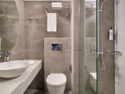 Moderner Hotelbadezimmer mit weißem Waschbecken, Toilette und Duschkabine mit Glaswand.