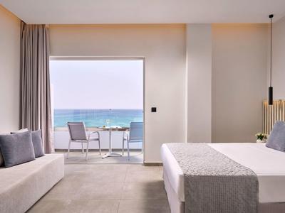 Modernes Hotelzimmer mit Meerblick, gemütlichem Sofa und großem Bett in neutralen Farben.
