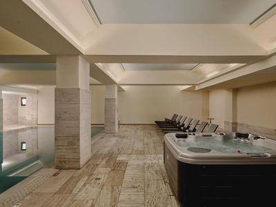 Moderner Innenpool mit Jacuzzi und bequemen Liegen in einem Hotel.