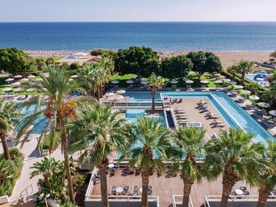 Luxuriöses Hotel mit Pools und Palmen direkt am Sandstrand und Meer.