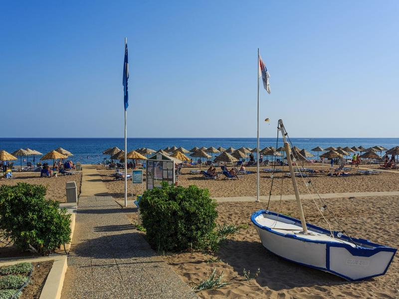 Beach with sun loungers, umbrellas, and a small boat on the sand under a clear sky.
