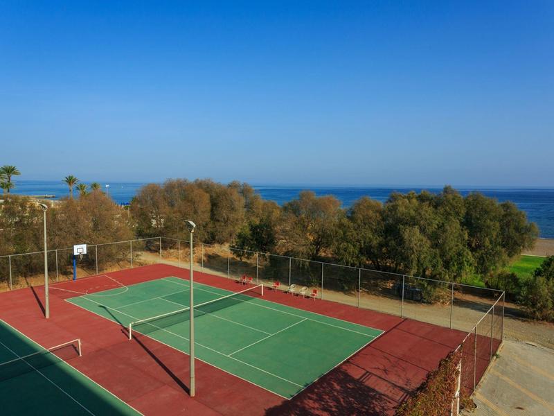 Outdoor tennis courts with sea view and clear blue sky in the background.