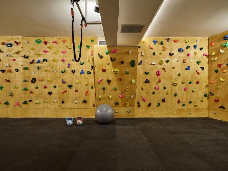 Climbing wall with colorful holds in a hotel gym with exercise ball and mats.