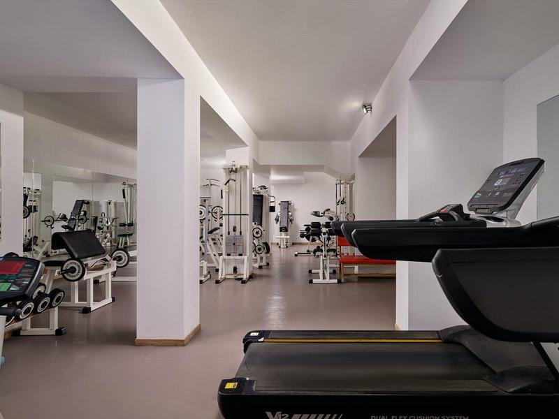 Modern gym with various exercise machines and treadmills in a hotel.