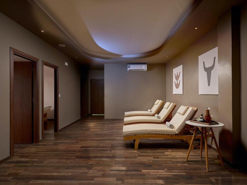 Relaxation room with lounge chairs, wooden floor, and warm lighting in a hotel.