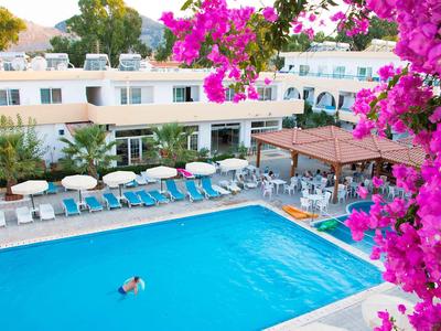 Widok na basen na świeżym powietrzu z leżakami i kwitnącymi różowymi kwiatami w hotelu.