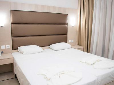 Moderní hotelový pokoj s velkou postelí, dvěma polštáři a nočními stolky.