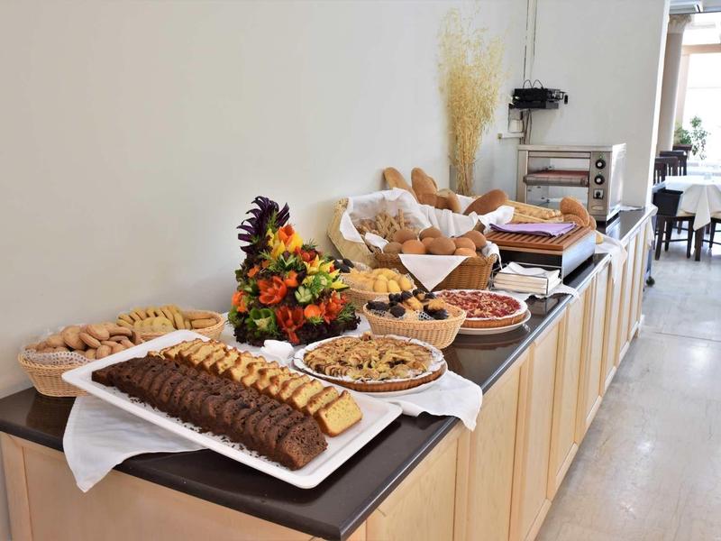 Bufet s výběrem pečiva, sušenek a chleba v světlé místnosti.