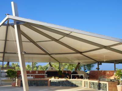 Area esterna moderna con tenda bianca e mobili in legno sotto un cielo sereno.