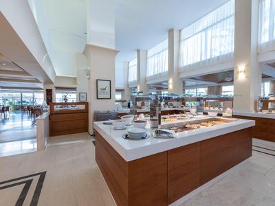 Ampia zona buffet in un ristorante luminoso con design moderno e rivestimento in legno.