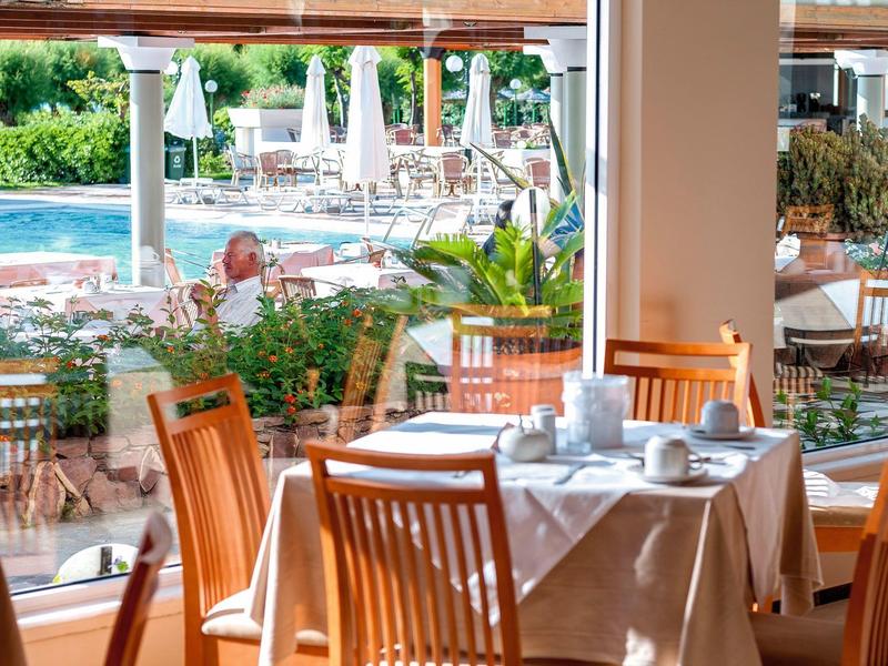 Restaurace s prostřeným stolem a výhledem na bazén a lehátka venku.