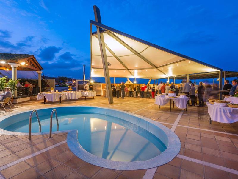 Osvětlený bazén s krytou venkovní restaurací za soumraku.