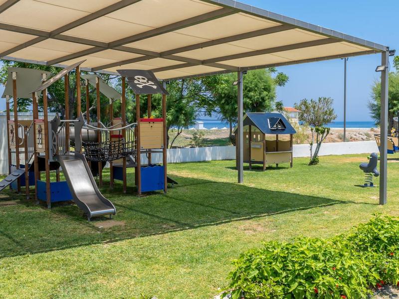 Dětské hřiště s klouzačkou a pískovištěm pod přístřeškem u pláže