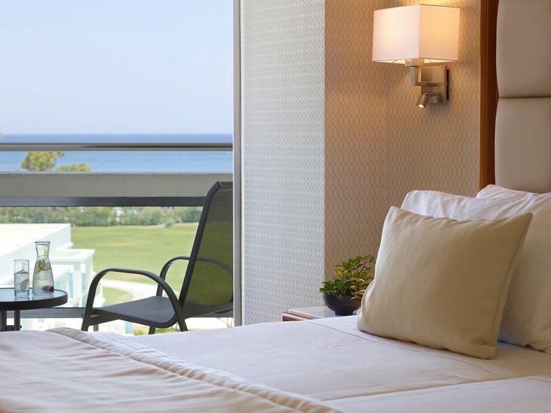 Moderní hotelový pokoj s pohodlnou postelí a výhledem na balkon a moře.