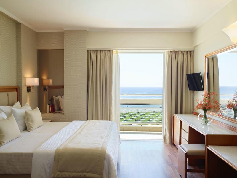 Světý hotelový pokoj s manželskou postelí, psacím stolem, balkonem a výhledem na moře