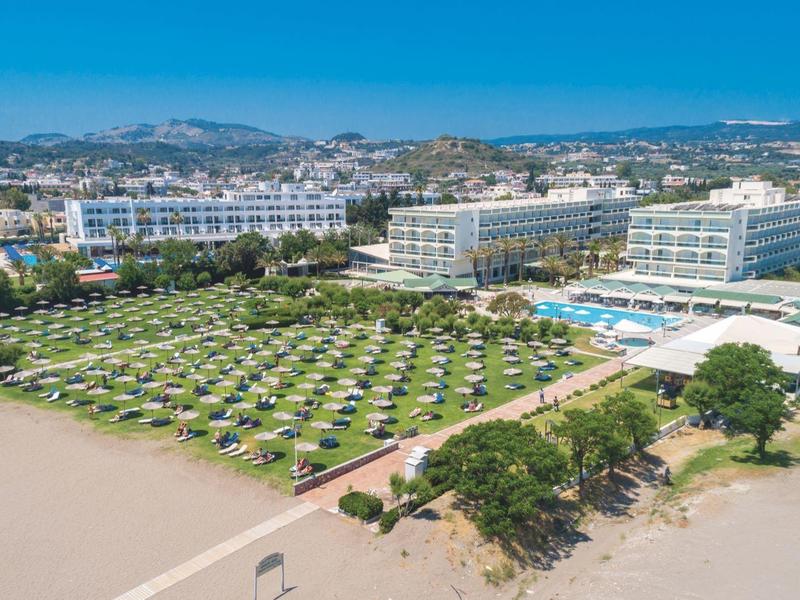 Velký hotelový areál s mnoha lehátky na pláži a výhledem na modré moře.
