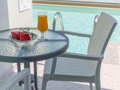Mesa de cristal con bebida y regalo junto a una piscina con zona exterior para sentarse.