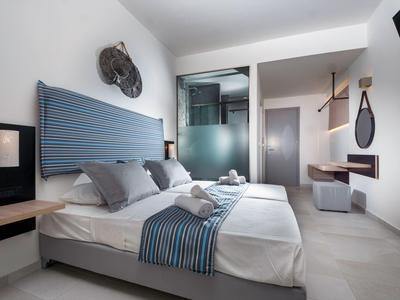 Modernes Hotelzimmer mit zwei Betten, stilvollem blauen Kopfteil und grauen Akzenten.