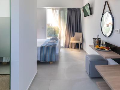 Bright hotel room with bed, chair, mirror, and drinks on the sideboard.