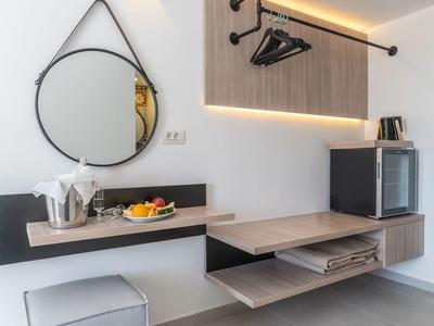 Modern hotel area with round mirror, cube seat, and minimalist coat rack.