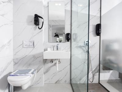 Modern bathroom with marble tiles, toilet, sink, and glass shower.