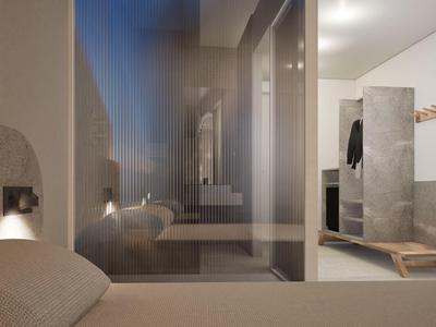 Modern hotel room with light walls, beige bed, and open bathroom with glass partition.