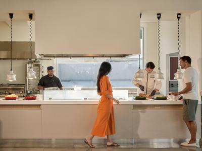 Bar dell'hotel moderno con barista e ospiti, illuminazione calda e design minimalista.
