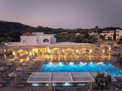 Piscina moderna dell'hotel al crepuscolo con sedie a sdraio e terrazza illuminata.