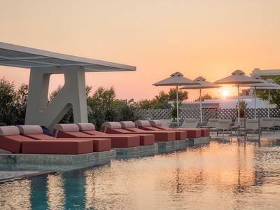Piscina dell'hotel con lettini e ombrelloni al tramonto.