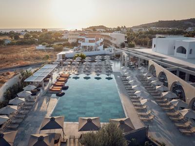Piscina moderna dell'hotel con lettini e ombrelloni in paesaggio soleggiato al tramonto.