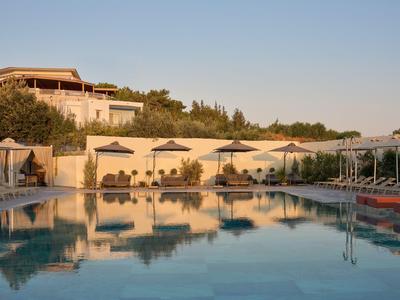 Grande piscina con lettini e ombrelloni in un resort hotel al tramonto.