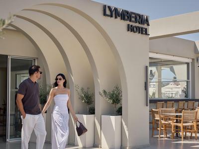 Una coppia cammina davanti a un hotel bianco moderno con archi curvi e area esterna.