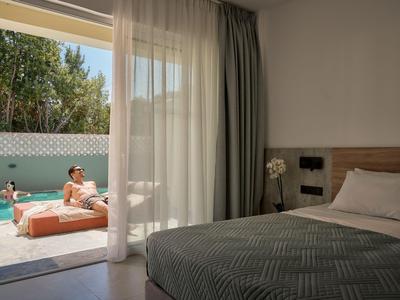 Camera d'albergo luminosa con vista su terrazza esterna e piscina.