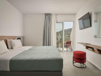 Camera d'albergo moderna con letto grande, balcone e vista sulle montagne.
