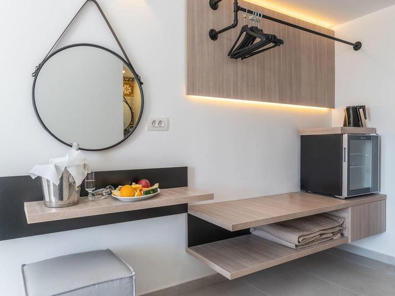 Modern hotel area with round mirror, cube seat, and minimalist coat rack.