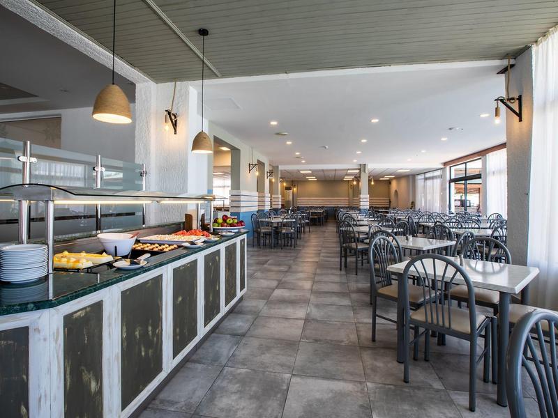 Bright breakfast room with buffet area, gray chairs, and tables.