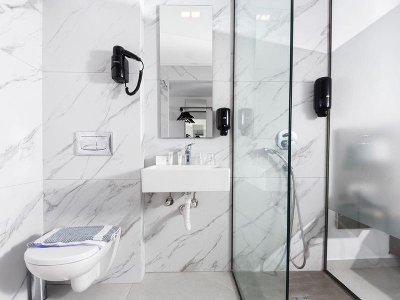Modern bathroom with marble tiles, toilet, sink, and glass shower.