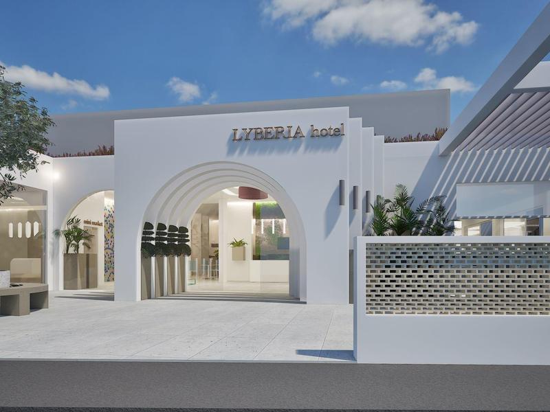 Modern white hotel entrance under clear sky with trees and benches.