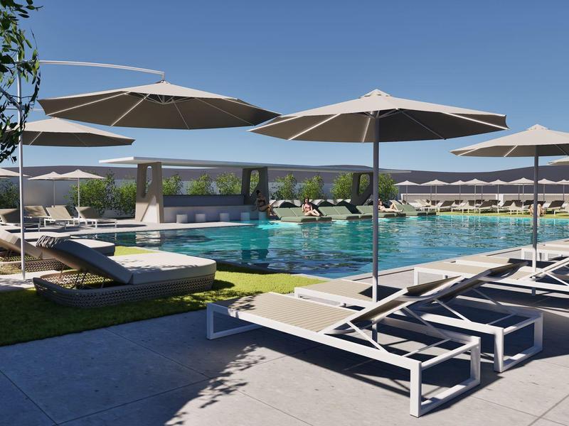 Modern pool area with sun loungers and umbrellas under a blue sky.