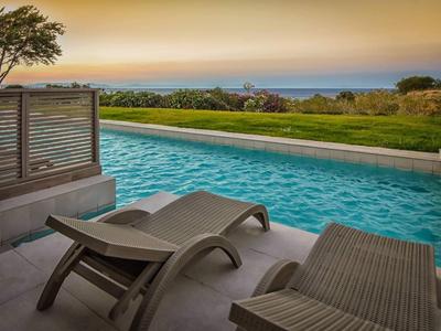 Area piscina rilassante con lettini e vista sul paesaggio al tramonto.