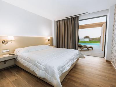 Modern hotel room with double bed and access to terrace with garden view.