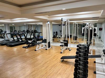 Modern gym with treadmills and weight machines on light brown wood floor.